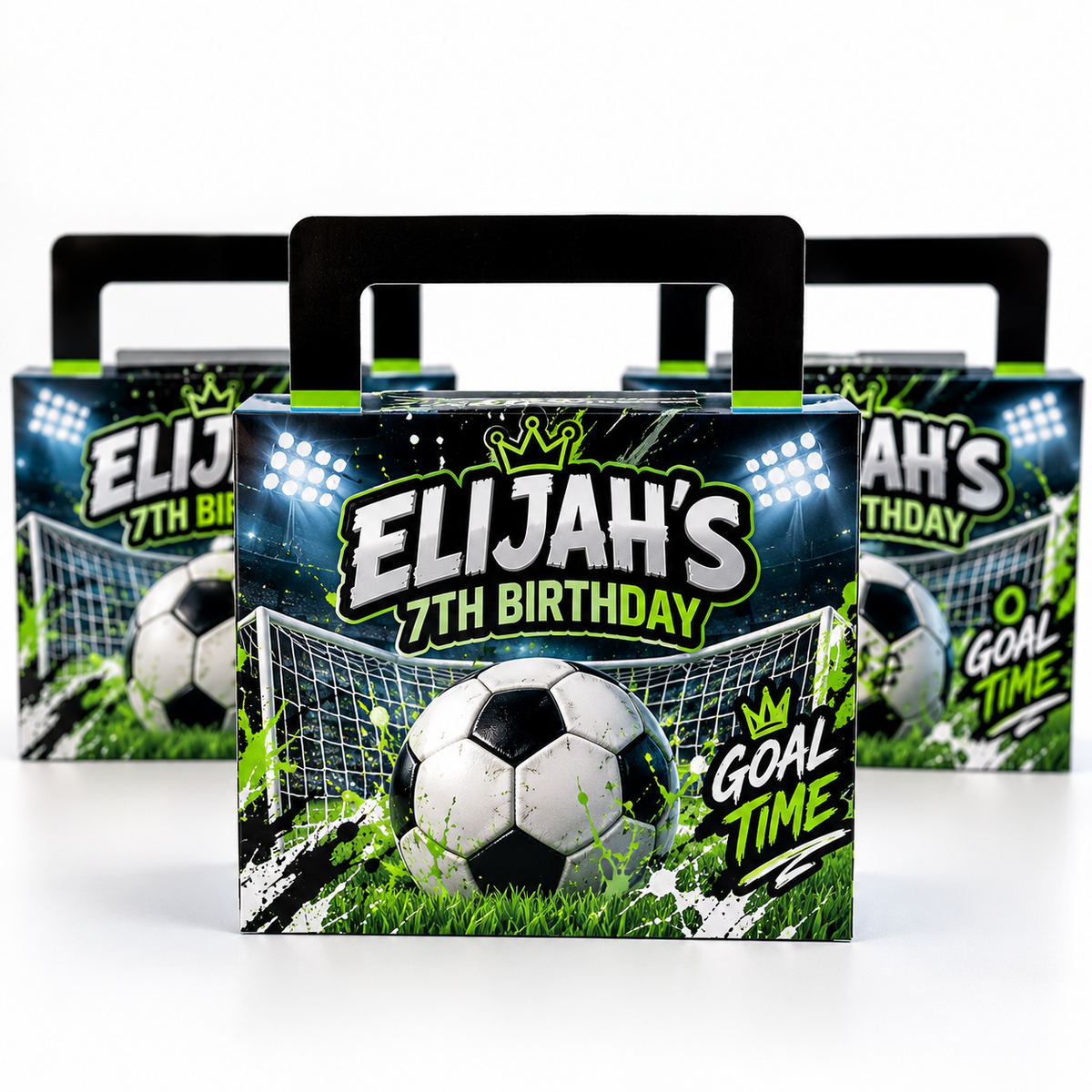 Three soccer-themed party favor boxes with black handles, featuring a soccer ball, goal net, grass, and stadium lights on the front, with the text 'ELIJAH'S 7TH BIRTHDAY' and 'GOAL TIME'.