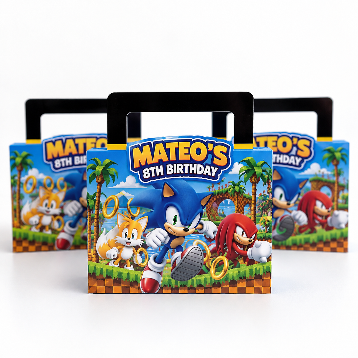 Three Sonic-themed party favor boxes with black handles, featuring colorful artwork of Sonic, Tails, and Knuckles with the text 'MATEO'S 8TH BIRTHDAY' on a white background.